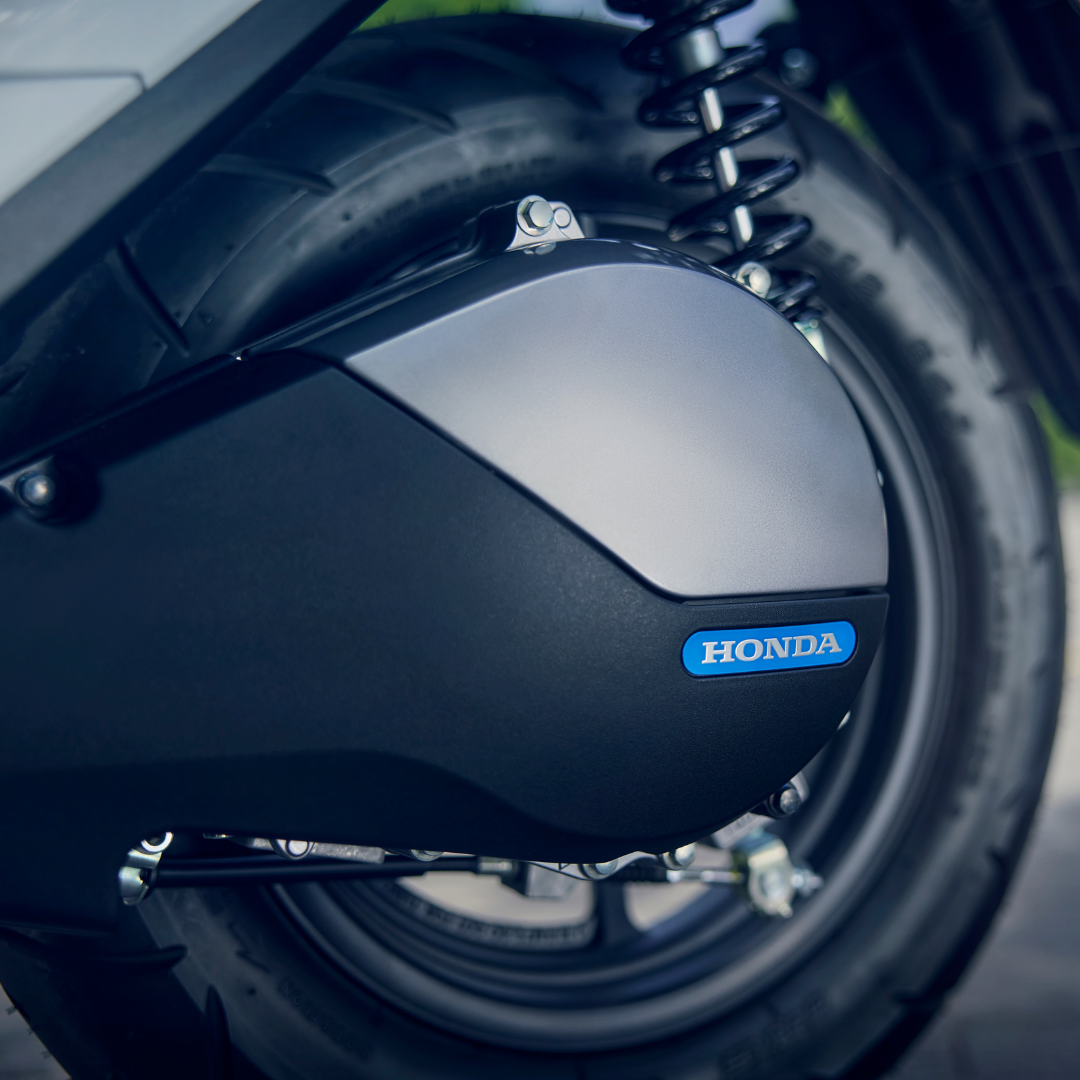 Close-up of a Honda scooter engine cover and rear wheel.