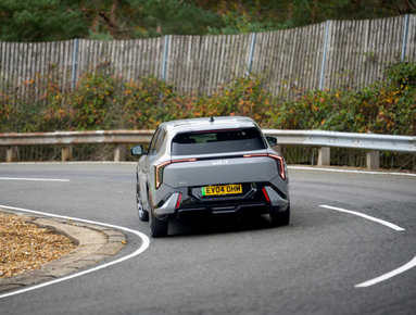 Silver car driving on a curved road, rear view.
