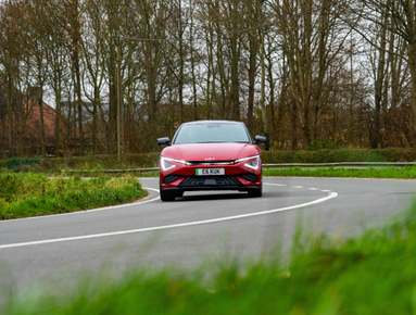 Red car driving on a curved country road.