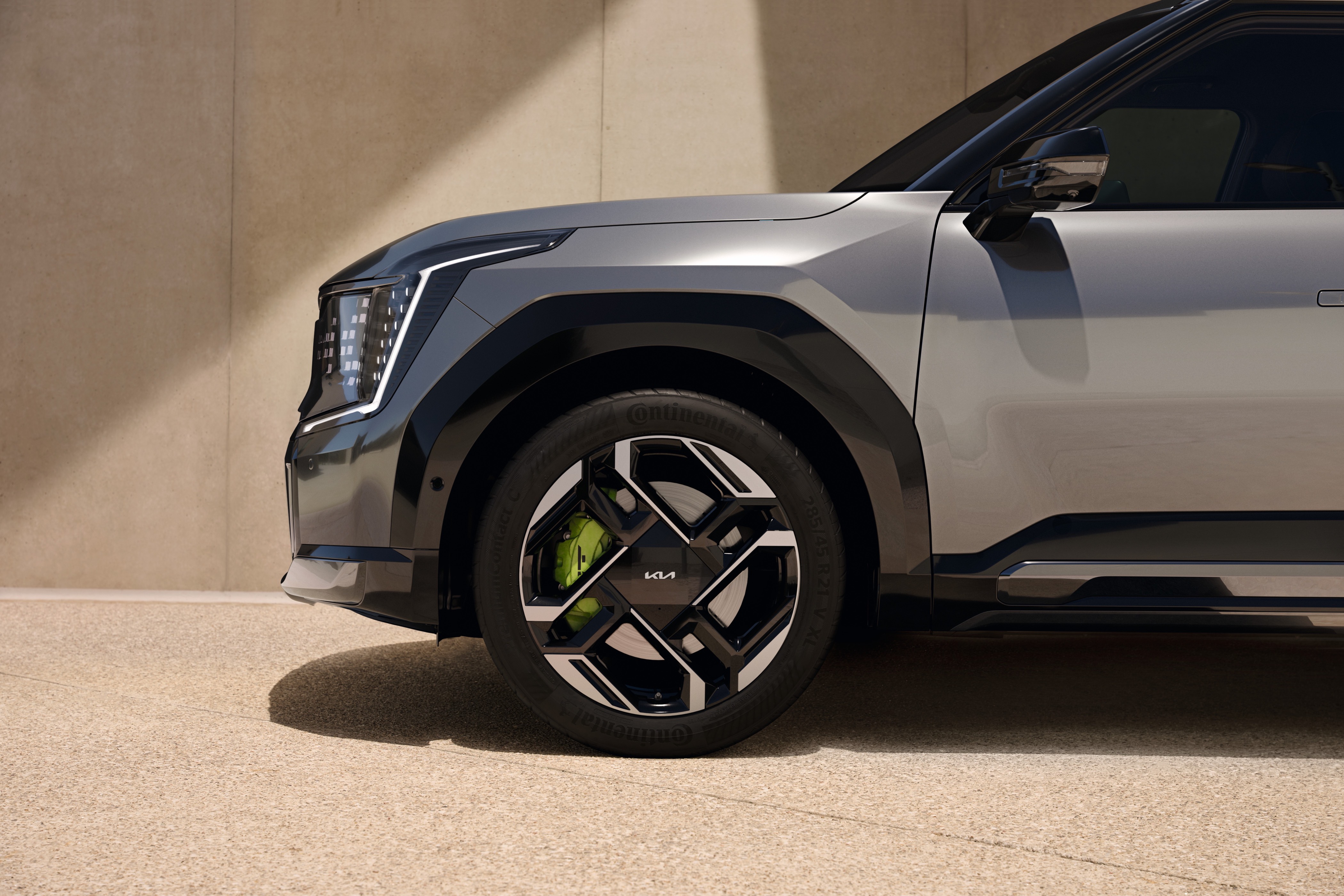 Front side view of a grey car, focusing on the wheel and front headlight design.