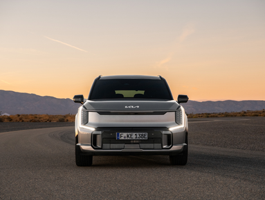 Front view of a silver SUV car parked on a road at sunset.