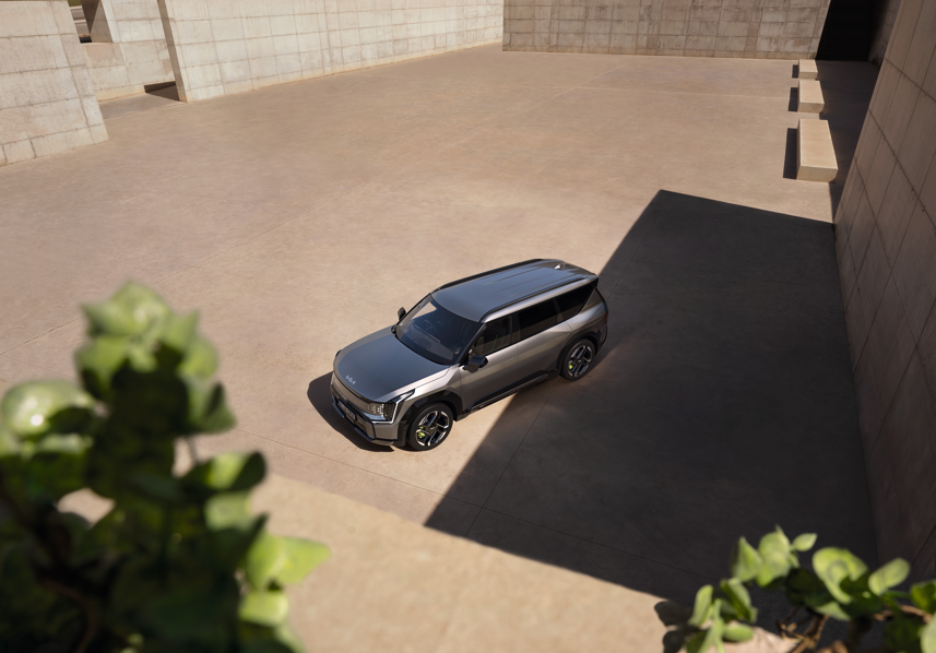 Silver SUV parked in a large concrete area with shadows and a plant in the foreground.
