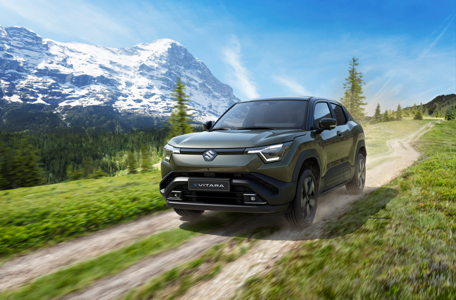 A green SUV driving on a dirt road in a mountainous landscape.