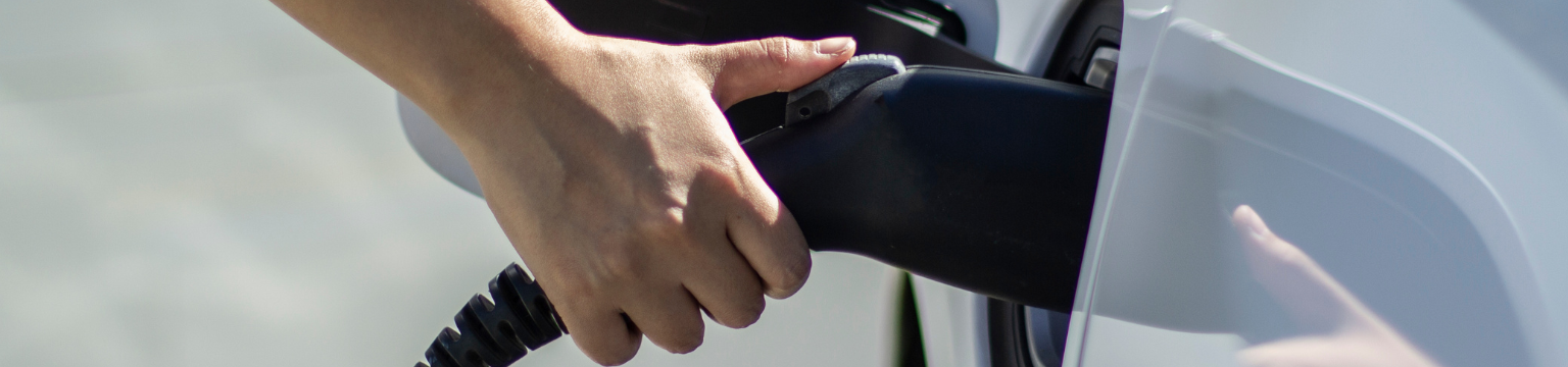 Hand plugging a charger into an electric vehicle.