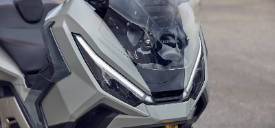 Close-up of a grey sporty motorbike front with a windshield and distinctive headlights.