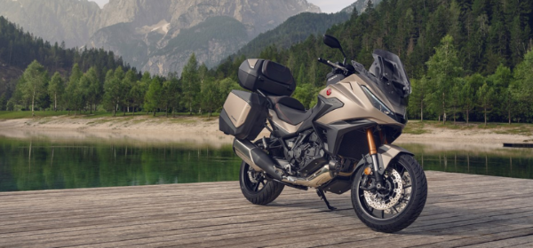 Motorbike parked on a wooden platform beside a lake and forested hills.