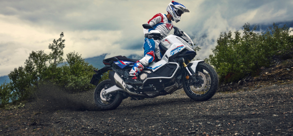 Motorcyclist riding Tri-colour HONDA X-ADV up hill off road