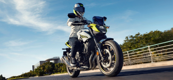 Person riding a yellow and black motorcycle wearing a white jacket and helmet.