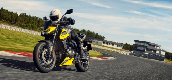 Motorcyclist riding a yellow and grey Honda CB750 Hornet navigating around a track corner