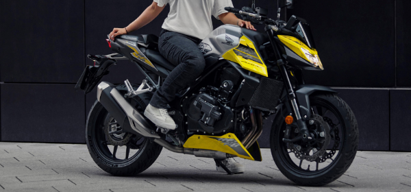 Person sitting on a yellow and black Honda motorcycle.