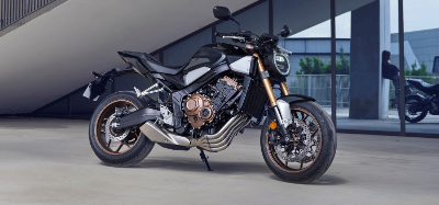A parked black motorcycle with bronze-coloured engine and wheels.