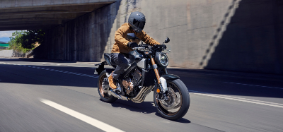 Person riding a motorcycle on the road wearing protective gear and a helmet.