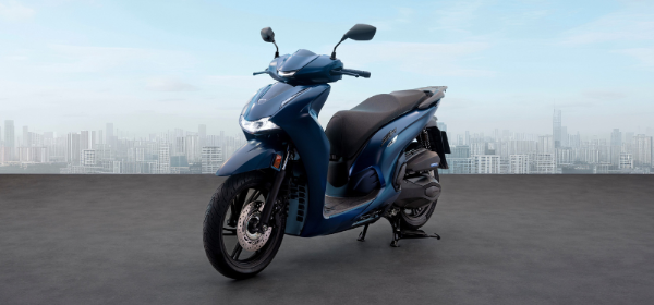 Blue scooter parked on concrete pavement next to a modern building.