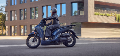 Motorcyclist Riding a blue Honda SH350i Scooter on a city road