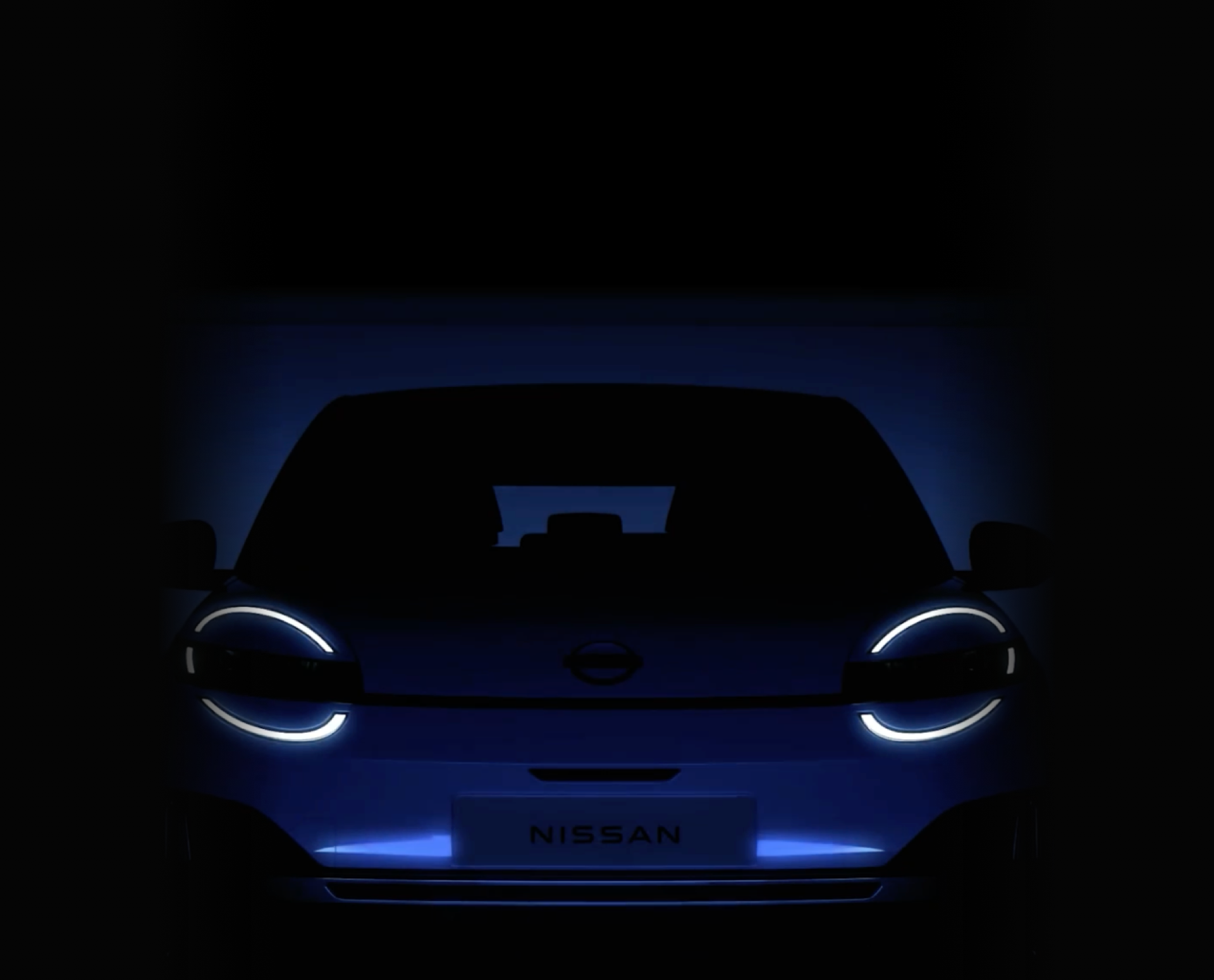 Front view of a car with illuminated headlights in a dark setting.
