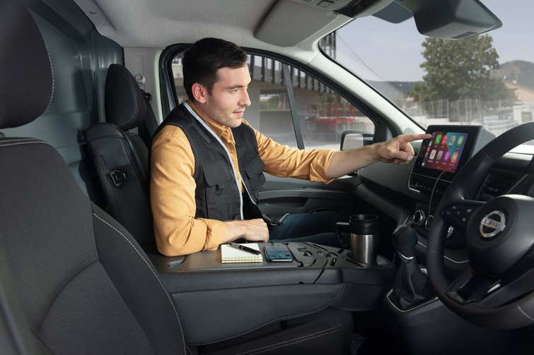 Man sitting in a vehicle, interacting with a touchscreen display on the dashboard.