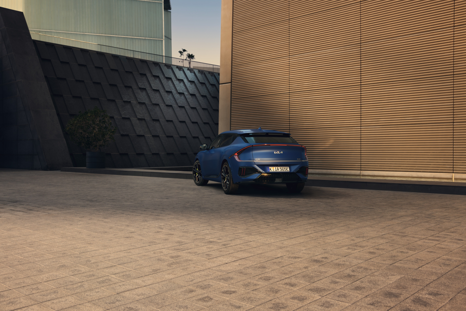 A blue electric vehicle parked near a modern building.