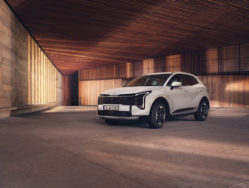 White SUV parked in a wooden ceiling setting, front wheels turned slightly outward.