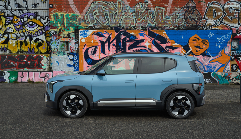 Blue compact SUV parked in front of a brick wall with colourful graffiti.