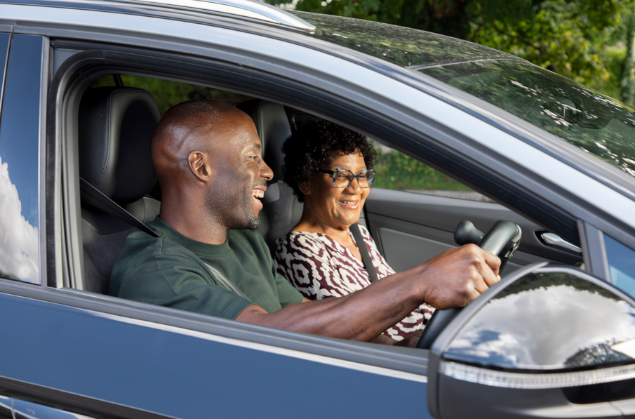 Two people smiling while seated in a car.