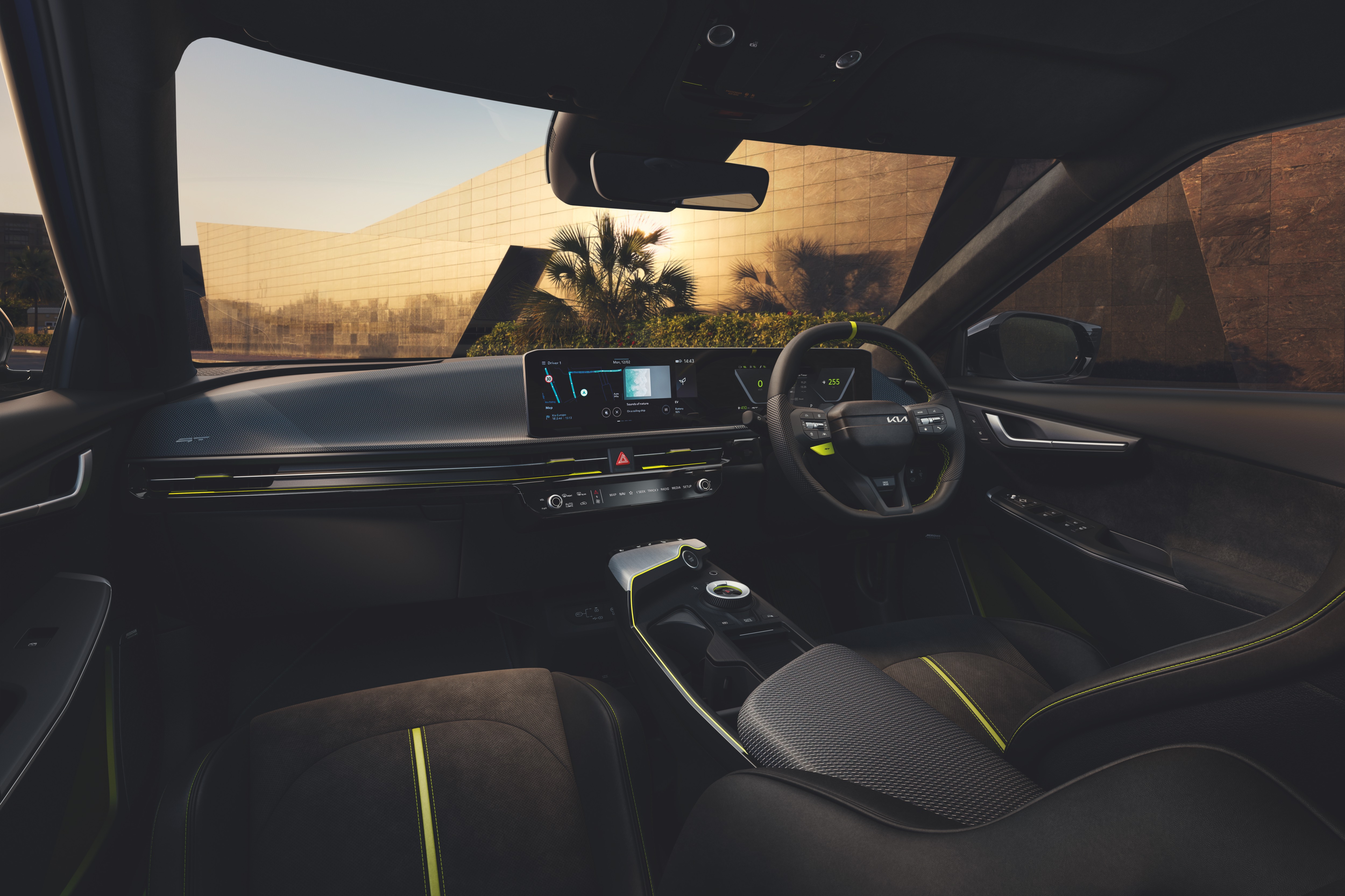 Car interior with modern dashboard and steering wheel, outside cityscape visible through windows.