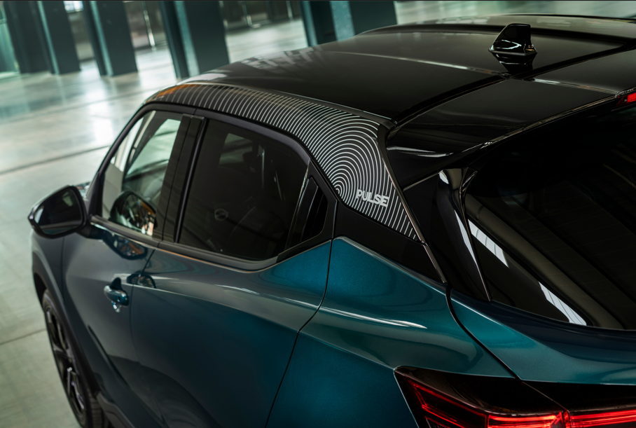 Side rear angle of a teal car with a patterned roof detail.