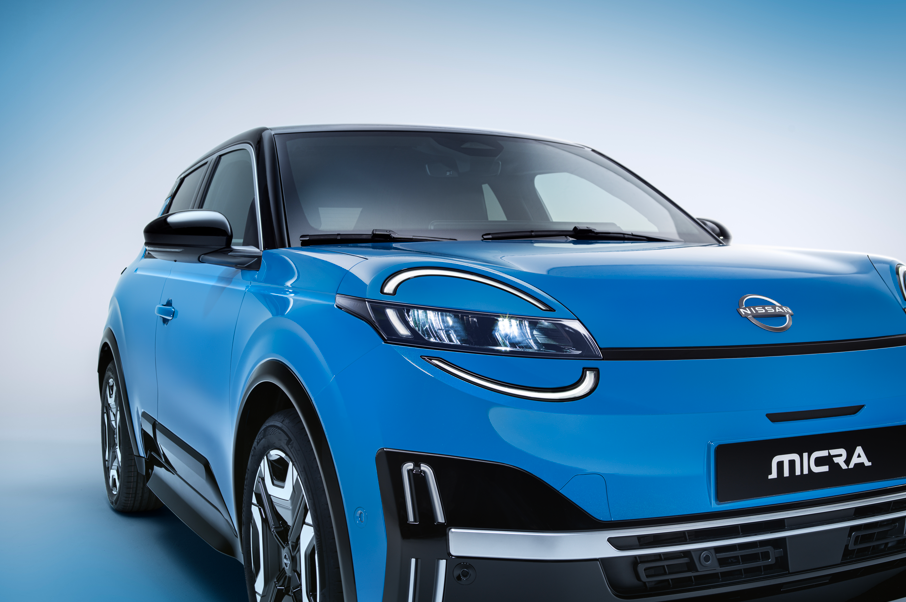 Blue Nissan Micra car, front-side view, showcasing headlights and grille.
