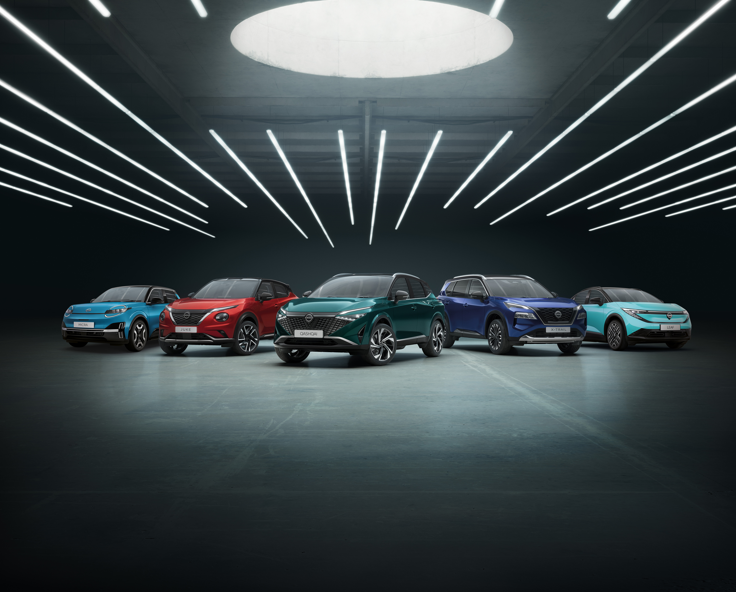 Five diverse-coloured MG cars lined up in a showroom with overhead lights.