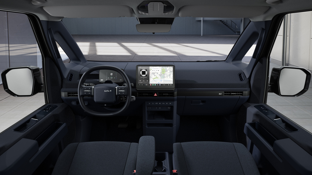 Interior view of vehicle dashboard with steering wheel and digital display screen.