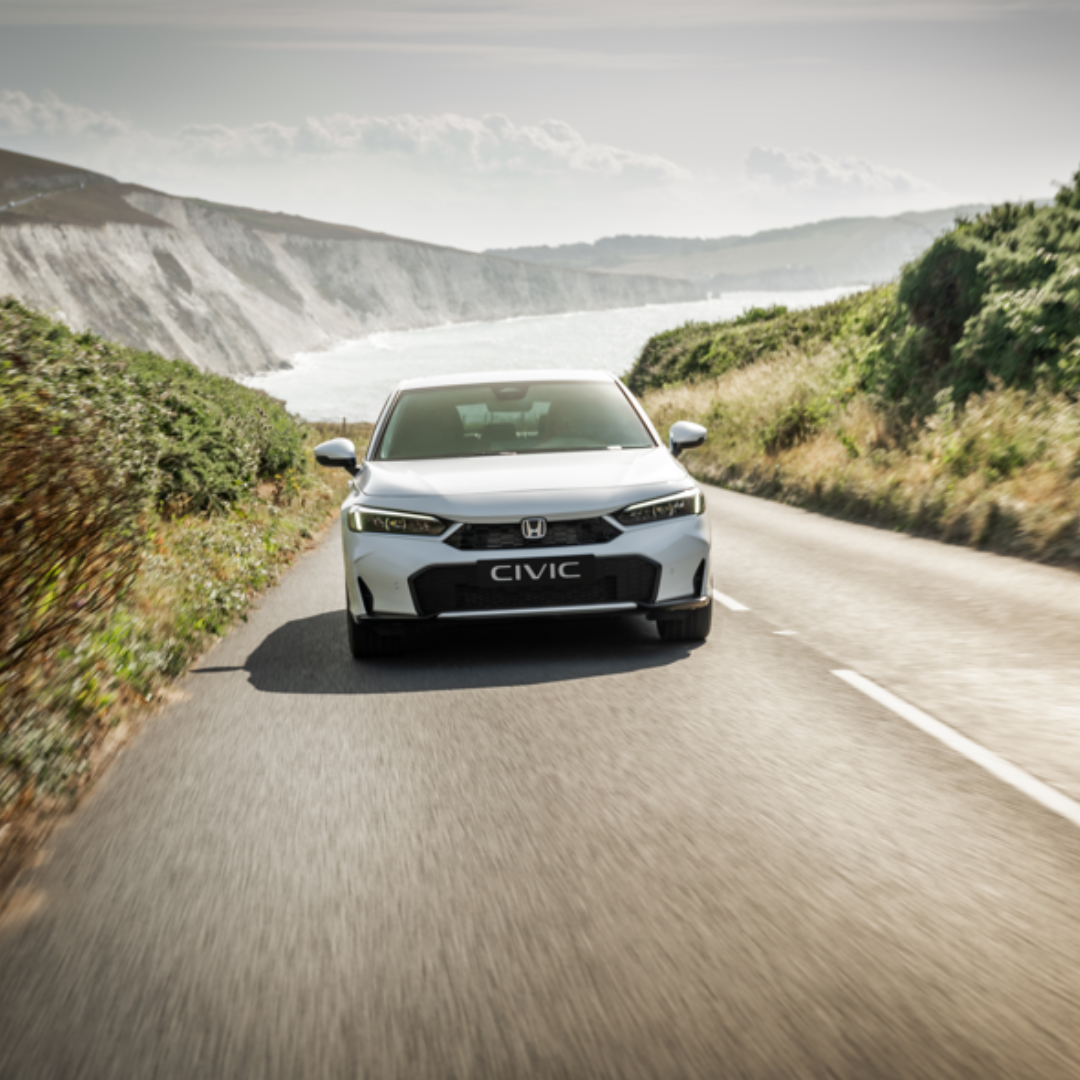 Front view of a white Honda Civic driving on a coastal road.