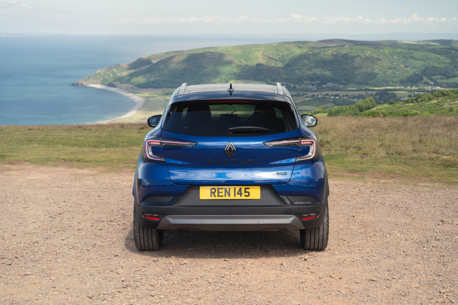 Rear view of a blue Renault Captur parked overlooking a coastal landscape.