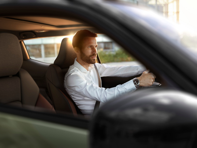 Man in a white shirt driving a car viewed from the passenger side.
