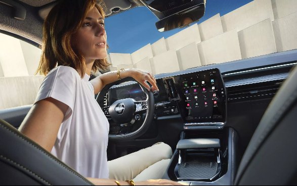 Woman driving with hand on steering wheel inside a modern car.