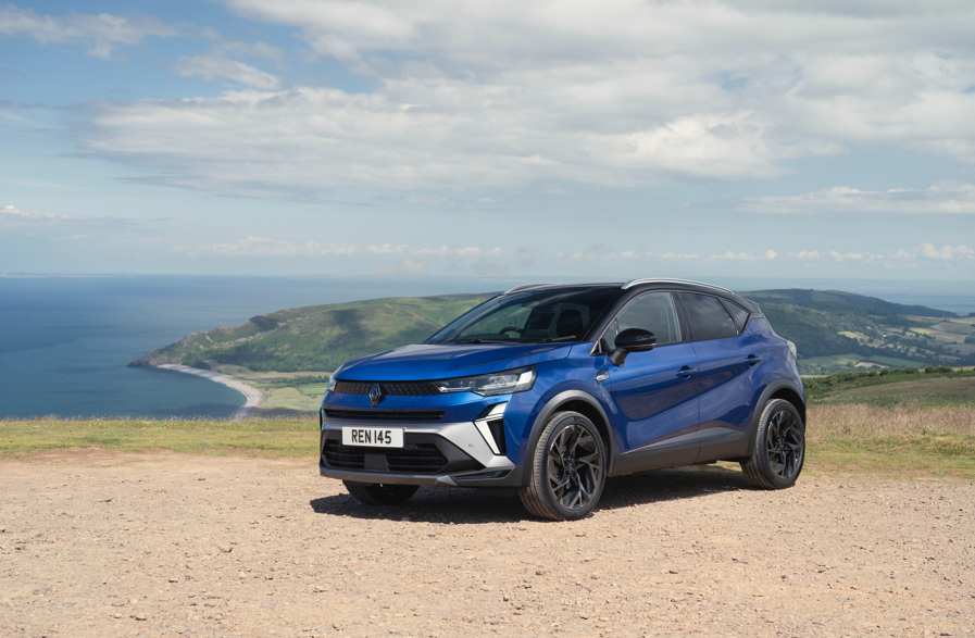 Blue SUV parked on a hilltop overlooking a coastal landscape with cliffs.