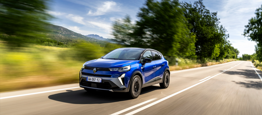 Blue SUV driving on a two-lane road with trees and hills in the background.