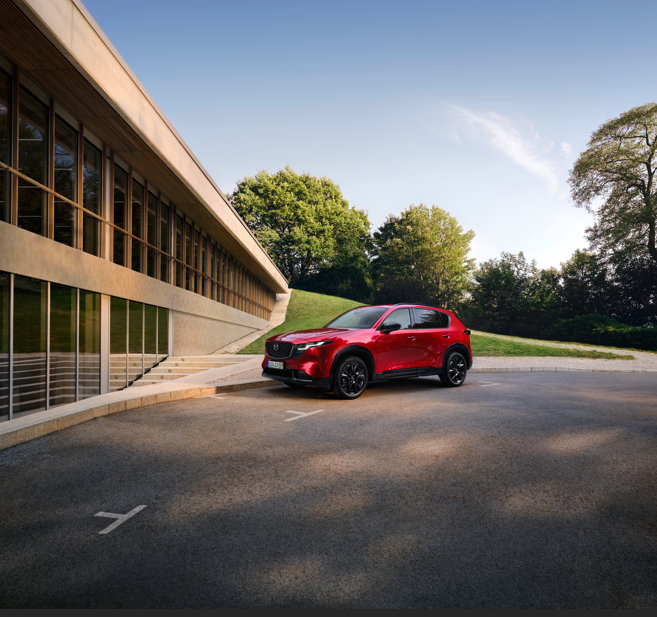 Red SUV parked beside a modern building with large windows.