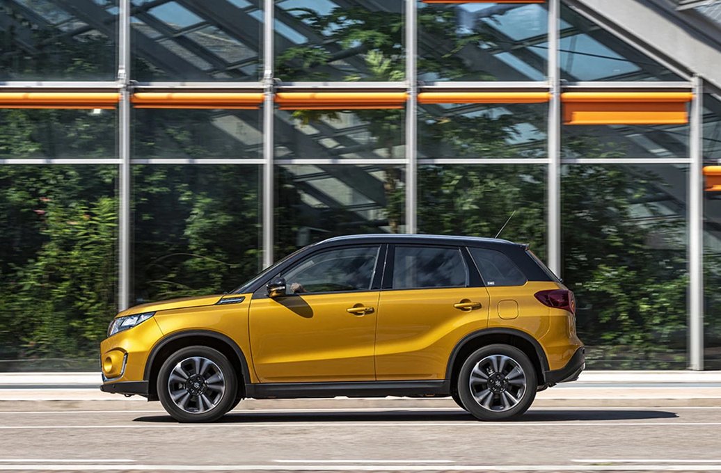 A yellow SUV driving on a sunny day.
