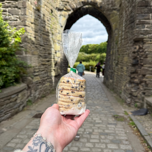Hand holding a packet of wrapped oatcakes in front of a stone archway.
