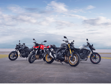 Four motorbikes parked side by side on a concrete surface.